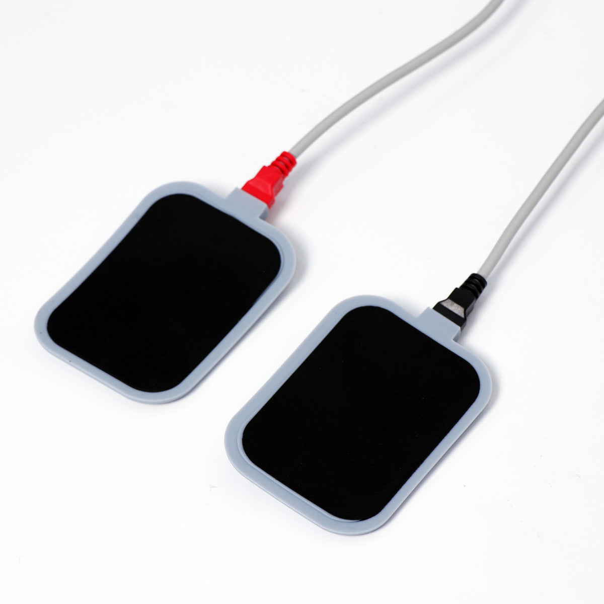 Pair of rectangular body treatment electrode pads with red and black connector cables for professional aesthetic machine treatments.